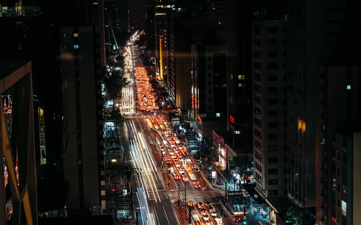 Vista noturna da Avenida Paulista, em São Paulo, com fluxo de veículos.